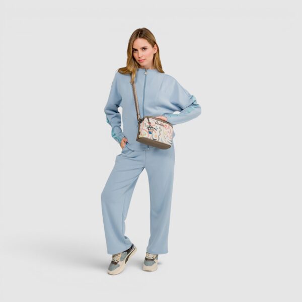 Imagine de femeie în outfit casual, pantaloni și hanorac, purtând geantă de mână, stil relaxat și mo.
